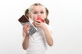 Little cute girl chooses apple over chocolate, preference of healthy food over unhealthy and unhealthy. Royalty Free Stock Photo