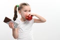 Little cute girl chooses apple over chocolate, preference of healthy food over unhealthy and unhealthy. Royalty Free Stock Photo