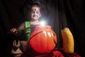 Little cute girl costumed as a witch spells a sweet pumpkin Royalty Free Stock Photo