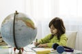 Little cute girl doing homework at home - Pre or elementary schooler girl drawing and painting the world on the school notebook Royalty Free Stock Photo