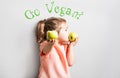 Little cute girl eating apple. inscription Go Vegan