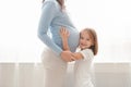 Little cute girl embracing her pregnant mother belly Royalty Free Stock Photo