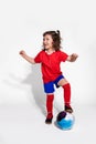 Little cute girl in football uniform and with ball on white background. Women`s football concept for kids