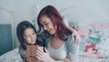 Little cute girl giving gift box to her young happy mom celebrating mothers day sitting on bed in cozy bedroom at home Royalty Free Stock Photo