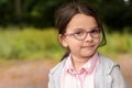 Little cute girl in glasses and a jacket on the street. Smart child schoolgirl on a walk Royalty Free Stock Photo