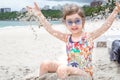 A little cute girl with glasses is playing in the sand on the beach by the sea Royalty Free Stock Photo