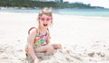 A little cute girl with glasses is playing in the sand on the beach by the sea Royalty Free Stock Photo