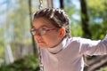 Little cute girl in glasses smiling rides on a swing at the playground in the park