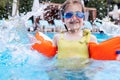 Little cute girl in goggles, yellow swimsuit and orange inflatable armlets swiming in pool hotel Royalty Free Stock Photo