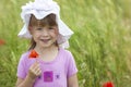 Little cute girl in a hat holding red flower and smiling Royalty Free Stock Photo