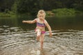 Little cute girl have fun playing with a spray of water in the river at summer. copy space Royalty Free Stock Photo