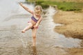 Little cute girl have fun playing with a spray of water in the river at summer. copy space Royalty Free Stock Photo