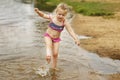 Little cute girl have fun playing with a spray of water in the river at summer. copy space Royalty Free Stock Photo