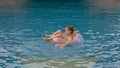 The little cute girl have fun in the pool. The child enjoy summer vacation in a swimming pool jumping, spinning, splash Royalty Free Stock Photo
