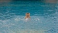 The little cute girl have fun in the pool. The child enjoy summer vacation in a swimming pool jumping, spinning, splash Royalty Free Stock Photo