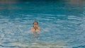 The little cute girl have fun in the pool. The child enjoy summer vacation in a swimming pool jumping, spinning, splash Royalty Free Stock Photo