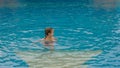 The little cute girl have fun in the pool. The child enjoy summer vacation in a swimming pool jumping, spinning, splash water. Royalty Free Stock Photo