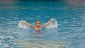 The little cute girl have fun in the pool. The child enjoy summer vacation in a swimming pool jumping, spinning, splash water. Royalty Free Stock Photo