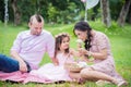 Girl with her parent sitting in park and watching flower Royalty Free Stock Photo