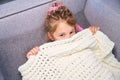 Little cute girl hiding under soft warm plaid lying on sofa Royalty Free Stock Photo