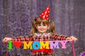 Little cute girl holds a garland with text `I love mommy` of colorful paper alphabet