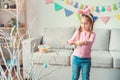 Little cute girl at home easter celebration concept in bunny ears decorating tree with eggs