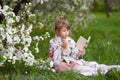 Little cute girl with ice cream reading a book  in the park. Child outdoors in blossoming spring garden Royalty Free Stock Photo