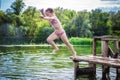 Little cute girl jumping off the dock into a beautiful river at sunset Royalty Free Stock Photo