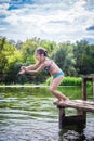 Little cute girl jumping off the dock into a beautiful river at sunset Royalty Free Stock Photo