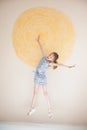 Little handsome girl jumping on wall with painted yellow sun background