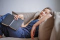 Little cute girl lies relaxed on sofa, fell asleep fatigue from reading book Royalty Free Stock Photo