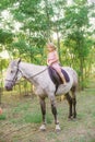 Little cute girl with light curly hair in a straw hat riding a horse at sunset Royalty Free Stock Photo