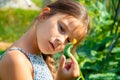Little cute girl with a long braid, eating a cucumber plucked from the garden