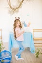 Little cute girl with long curly hair with little bunnies and Easter decor at home at the  table. Royalty Free Stock Photo