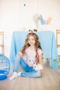 Little cute girl with long curly hair with little bunnies and Easter decor at home at the  table. Royalty Free Stock Photo