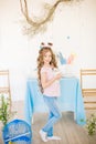 Little cute girl with long curly hair with little bunnies and Easter decor at home at the  table. Royalty Free Stock Photo