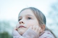 A little cute girl with long hair is sitting in a park seriously sad Royalty Free Stock Photo