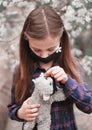 Little cute girl in mask has fun outdoors with her best friend toy cat. Royalty Free Stock Photo