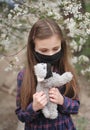 Little cute girl in mask has fun outdoors with her best friend toy cat. Royalty Free Stock Photo