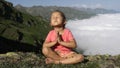 Little cute girl meditating on top of mountain