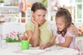 Little cute girl with mother drawing at home