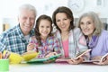 Little cute girl with mother and grandparents studying