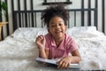 Little cute girl open book lying on the bed. little Girl reading a book in the home. Royalty Free Stock Photo