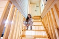 Little cute girl in pajama sit on stairs in cozy wooden tiny cabin house. Life in countryside Royalty Free Stock Photo
