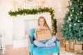 Little cute girl in pajamas near a Christmas tree with gifts and a bright fireplace decorated with garlands, needles and candles. Royalty Free Stock Photo