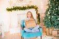 Little cute girl in pajamas near a Christmas tree with gifts and a bright fireplace decorated with garlands, needles and candles. Royalty Free Stock Photo