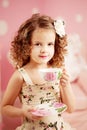 Little cute girl in a pink dress drinks tea with sweets in the c Royalty Free Stock Photo