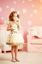 Little cute girl in a pink dress drinks tea with sweets in the c Royalty Free Stock Photo