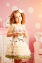 Little cute girl in a pink dress drinks tea with sweets in the c Royalty Free Stock Photo