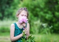 Little cute girl with pink fragrant peony plant. Child smelling flower in a summer garden Royalty Free Stock Photo